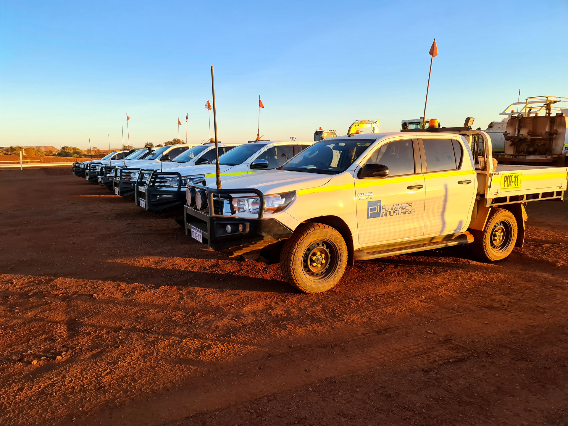 Several trucks parked in a dirt field, showcasing construction vehicles on a civil construction blog.