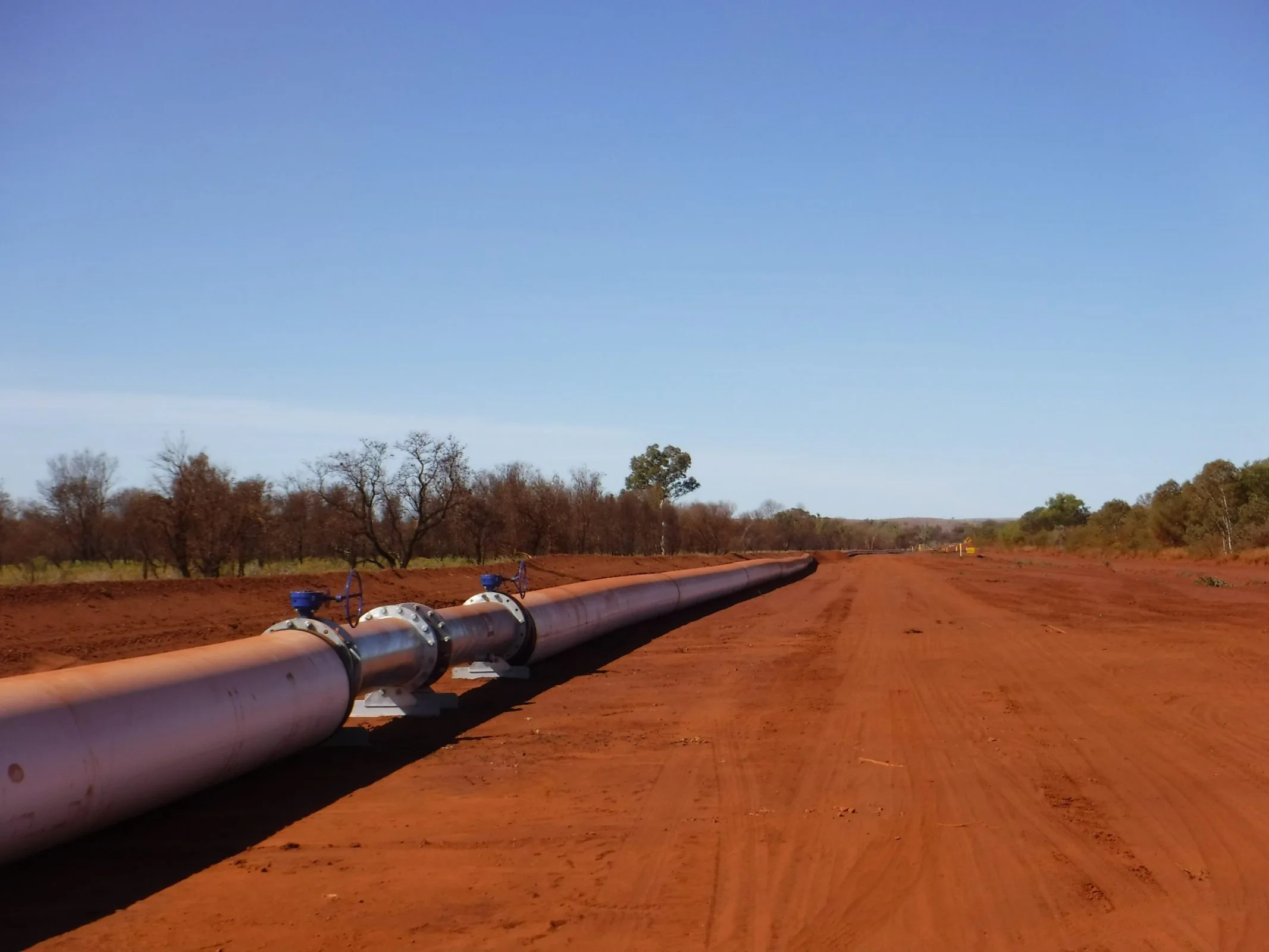 A large pipe on a dirt road with trees in the background, part of civil construction project.