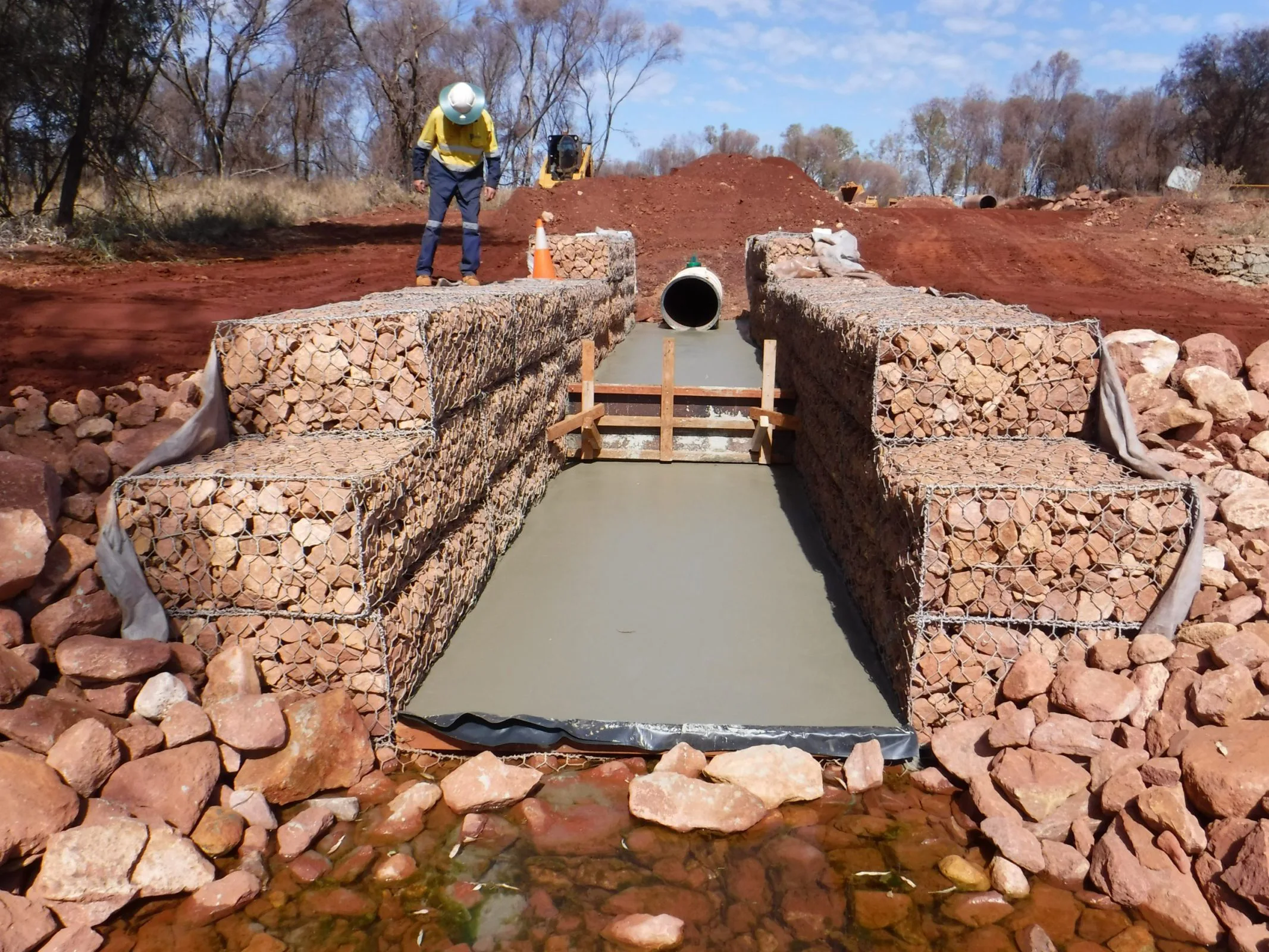 A civil construction worker standing next to a water pipe.