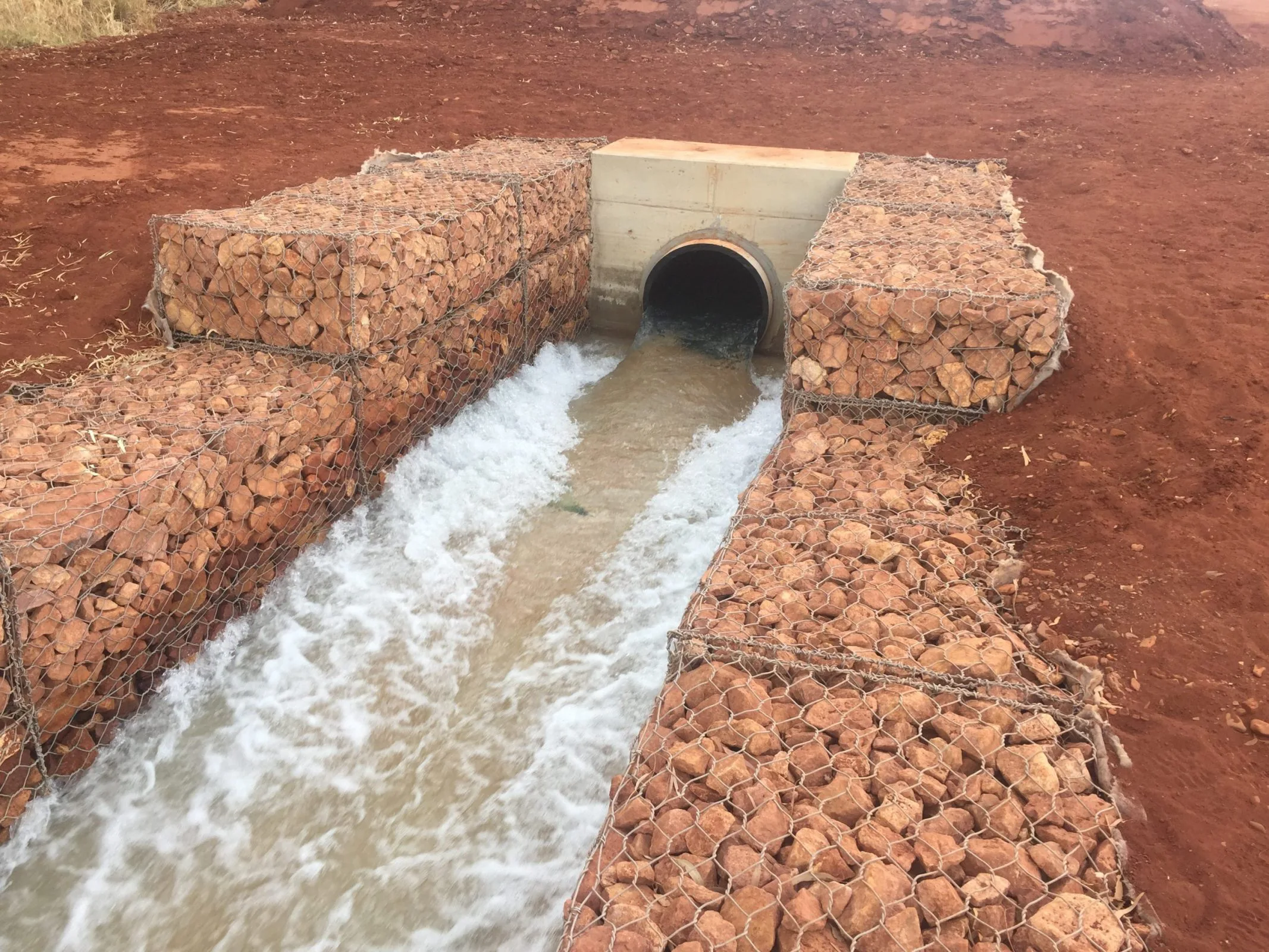 A civil construction project shows workers digging a water pipe into the ground.