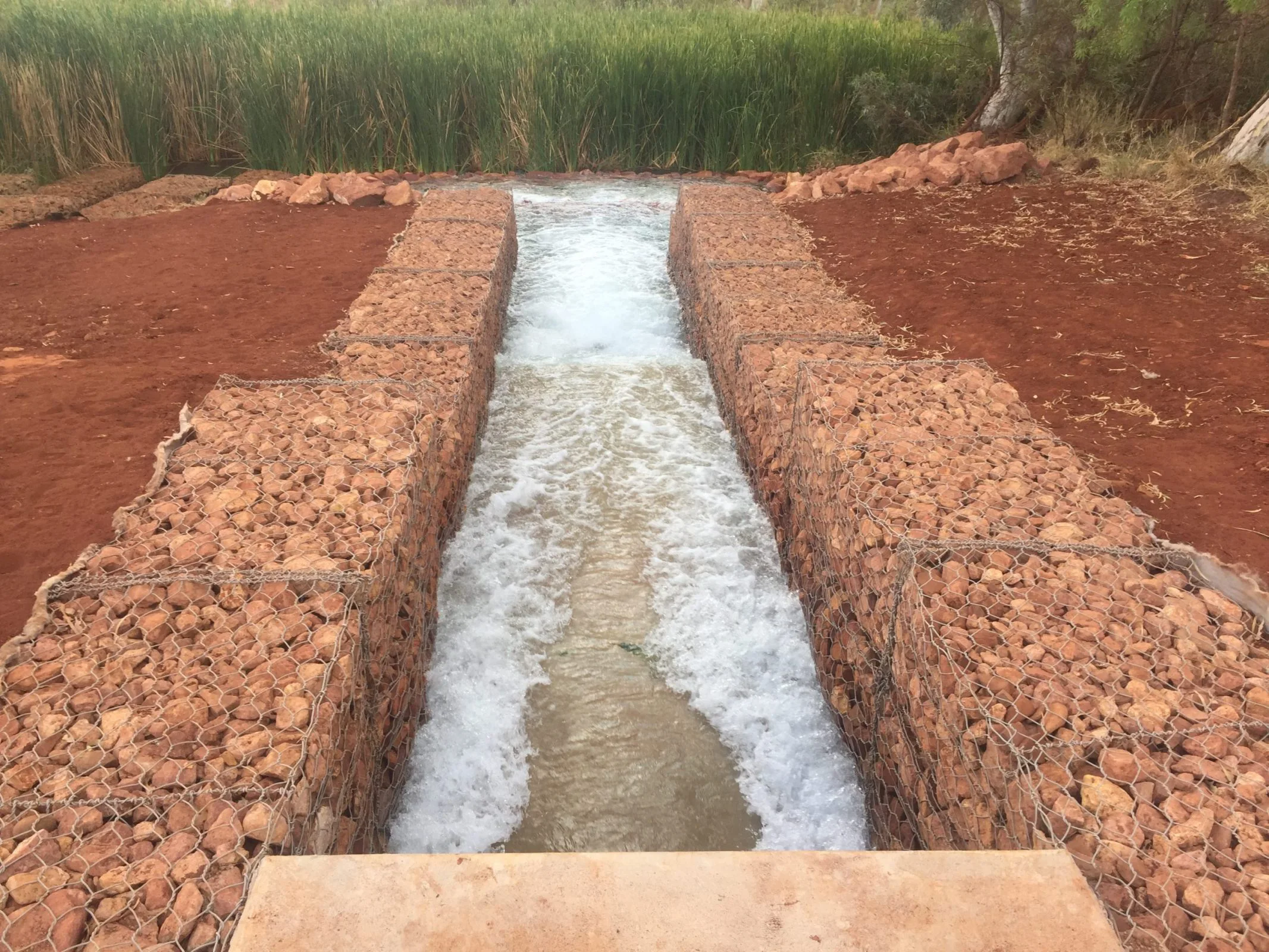 A civil construction project shows a waterway being built in the desert landscape.