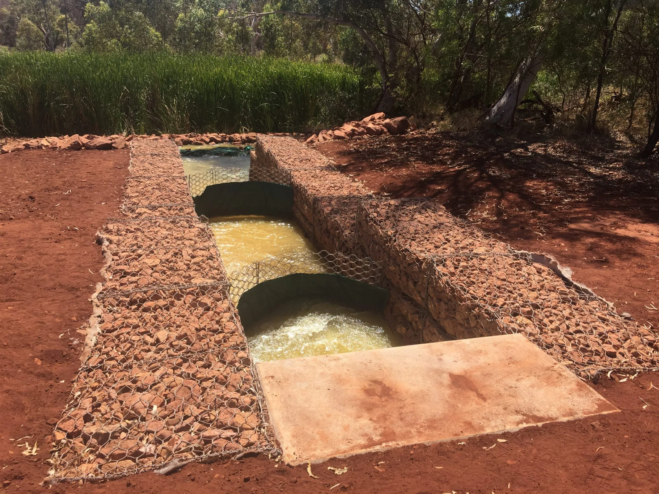 A civil construction well with a small pipe running through it, providing access to underground water sources.