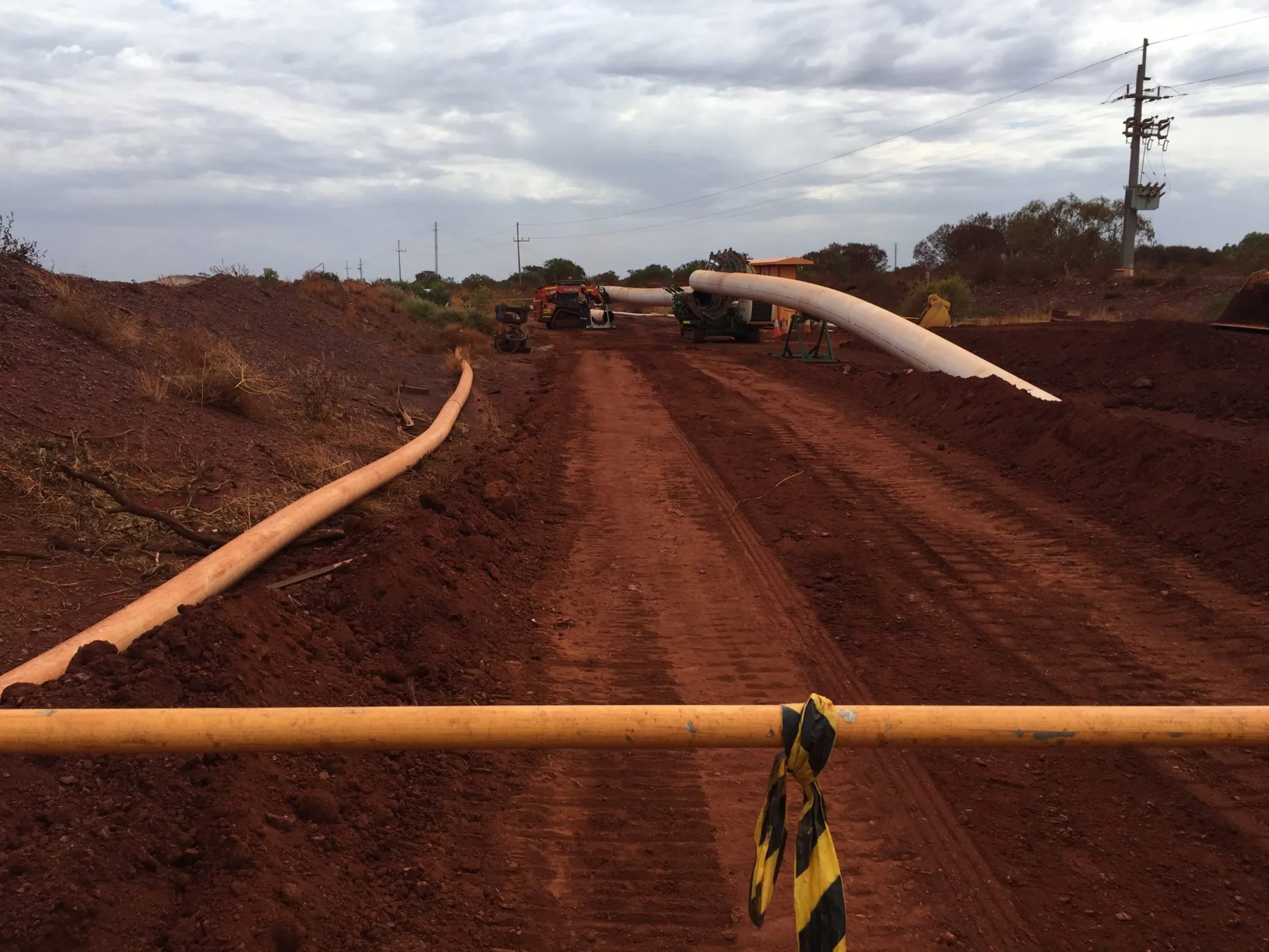 A civil construction crew installing a pipe on a dirt road.